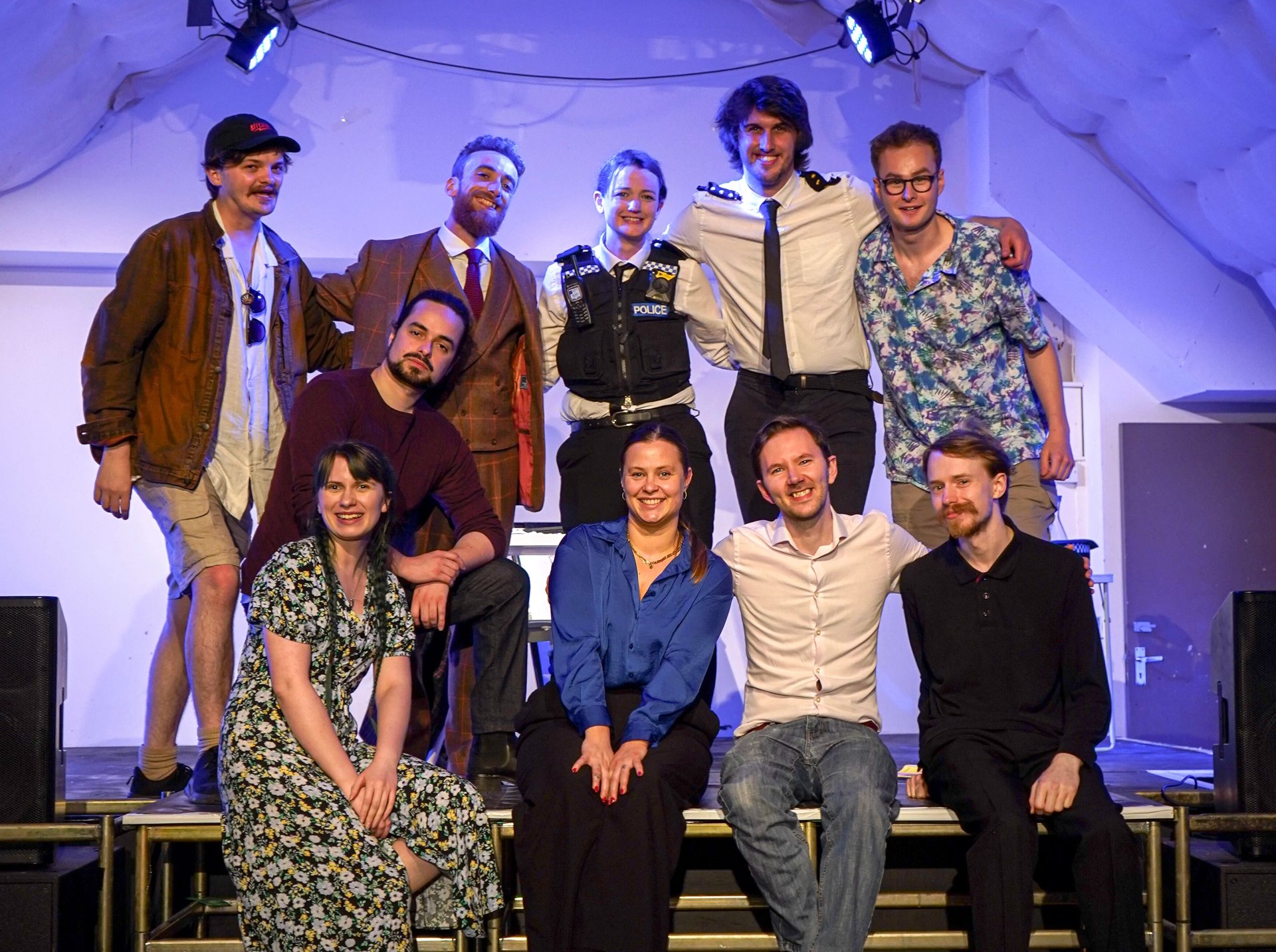 A stage photo of a group of actors and directors from the show Glitch. They are all posed next to each other and smiling.